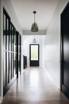 an empty hallway with black doors and white walls