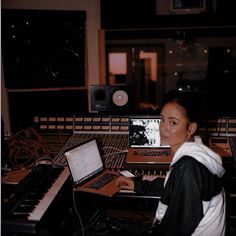 a woman sitting in front of a laptop computer on top of a desk next to sound mixing equipment