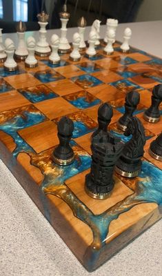 a wooden chess board with black and white pieces on it's sides, sitting on a table