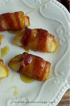 bacon wrapped apples on a white plate with honey syrup drizzled over them