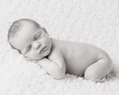 a newborn baby is sleeping on a white blanket with his head resting on his hands