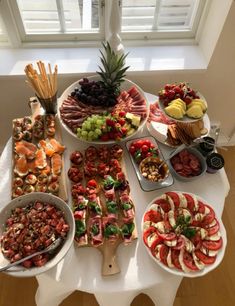 a table topped with lots of different types of food on plates next to a window