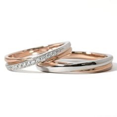 two gold and silver wedding rings with diamonds on top, set against a white background