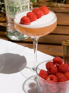 raspberries sit in small glasses on a table