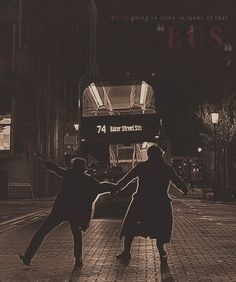 two people are dancing in the middle of an empty street at night, with a double decker bus behind them