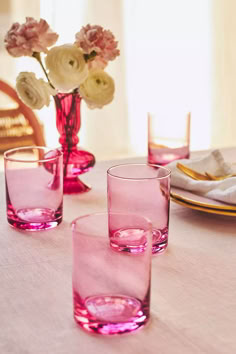 the table is set with pink glasses and plates