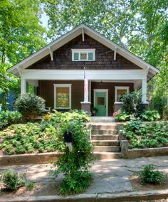 a small house with steps leading up to the front door and trees in the background