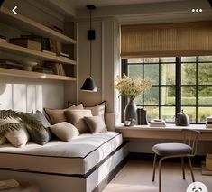 a living room filled with furniture next to a window covered in bookshelves and pillows