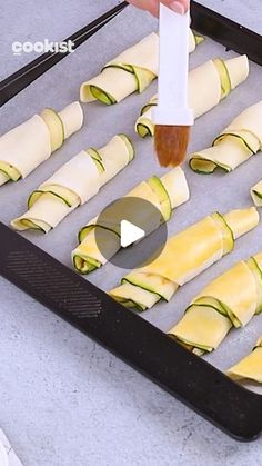 someone is spreading cheese on zucchini rolls