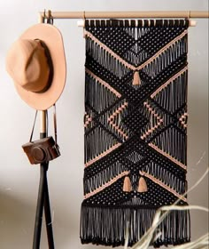 a wall hanging with a hat on top of it next to a tripod stand