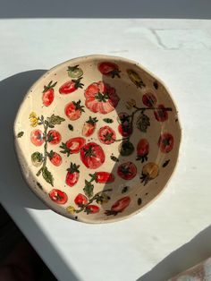 a bowl with tomatoes painted on it is sitting on a table next to a wall