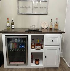 a white cabinet with liquor bottles on top and shelves above it in a home bar