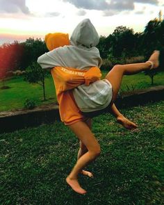 a person in an orange and white hoodie doing a handstand on the grass