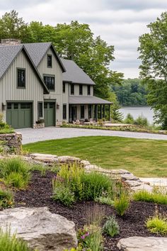 a large house sitting on top of a lush green field next to a lake with lots of trees