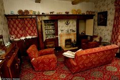 a living room with red couches and chairs next to a fireplace in the corner