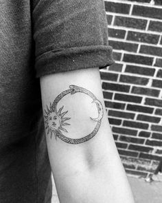 a woman's arm with a sun and moon tattoo on the left side of her arm