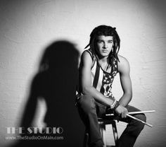 a young man sitting on top of a stool holding a pair of drums in his hands