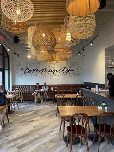 people sitting at tables in a restaurant with chandeliers hanging from the ceiling above them