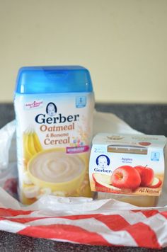 some food is sitting on top of a red and white striped napkin next to a bottle of gerber oatmeal