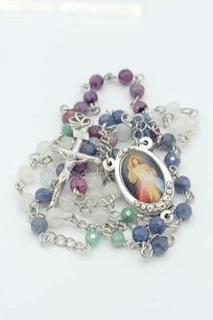 This unique rosary is absolutely one-of-a-kind and will never be duplicated.     It features the beautiful image of The Divine Mercy, set in oxidized Italian silver and embellished in delicate floral details.    The gemstones on this rosary are all-natural rubies, sapphires, moonstones, and emeralds.    The Hail Mary beads are alternating decades of rubies, sapphires, and moonstones (that flash bright blue) wired in stainless steel for durability.    The Our Father beads are beautiful bright gre Silver Spiritual Rosary Bracelet With Gemstone Beads, Spiritual Crucifix Jewelry With Faceted Beads, Spiritual Crucifix Gemstone Jewelry, Healing Jewelry With Miraculous Medal And Round Beads, Silver Natural Stone Round Beads Gemstones, Silver Natural Stones Round Beads Gemstones, Silver Rosary With 8mm Beads For Healing, Spiritual Silver Rosary Bracelet With Natural Stones, Silver Spiritual Rosary Bracelet For Healing