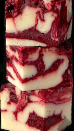 three pieces of red and white cake sitting next to each other on a black surface