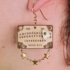 a person wearing earrings with letters and stars hanging from it's back earring