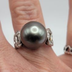 Beautiful Ring Set In 18k White Gold That Features An Approx 13mm Tahitian Black Pearl Surrounded By .53 Ctw Of Round Diamonds! This Ring Is Size 6 And Weighs 9.5 Gm. The Pearl Is High Luster With Some Natural Blemishes And Is Grey/Black/Purple In Color. There Are 18 Round Diamonds On Each Side Of The Band For A Total Carat Of .53. Color H Clarity Si1. It Is Stamped 750 (18k) And 053 On The Interior Of The Band. It Is A Lovely Estate Ring That Has Been Well Cared For! It Comes With A Recent Gia Appraisal For $3,250!! Luxury Tahitian Pearl Jewelry For Anniversary, Luxury Tahitian Pearl Anniversary Jewelry, White Gold Tahitian Pearl Jewelry With Diamond Accents, White Gold Tahitian Pearl Jewelry For Anniversary, Tahitian Pearl White Gold Jewelry With Diamond Accents, Formal White Gold Jewelry With Tahitian Pearl, Elegant White Gold Tahitian Pearl Ring, Luxury Tahitian Pearl Jewelry With Diamond Accents, Tahitian Pearl Jewelry With Brilliant Cut