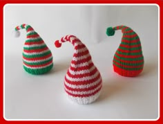 three knitted christmas hats sitting next to each other on a white surface with red and green stripes