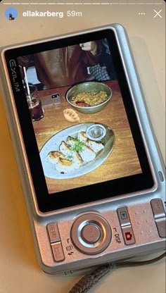 a cell phone sitting on top of a wooden table next to a bowl of food