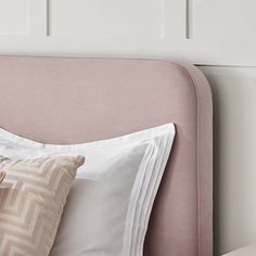 a pink headboard with two pillows and a white pillow on it's side