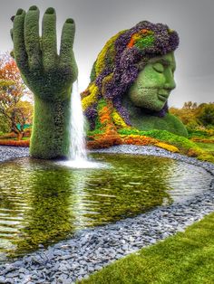 a large hand is in the middle of a body of water with plants growing out of it