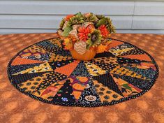 a vase filled with flowers sitting on top of a quilted tablecloth covered table