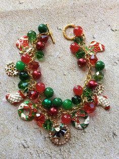 This Christmas charm bracelet is approx. 8 inches long and surrounded by green and red glass beads and holiday charms. #9 Green Christmas Jewelry For Festive Occasion, Green Beaded Bracelets For Holiday, Green Bracelet Jewelry For Holiday, Green Round Beads Jewelry For Holiday, Green Round Bead Jewelry For Holidays, Green Beaded Bracelet For Holiday, Handmade Green Bracelets For Holiday, Holiday Green Jewelry With Round Beads, Green Beaded Bracelets For Christmas