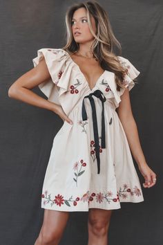 Embroidered bow ruffle sleeve taupe babydoll mini dress Material is Rayon Hang to dry Model is 5'7 wearing a small SHOP THE LOOK Small Medium Large Length 38" 39" 40" Bust 14.5" 15.5" 16.5" Flowy Mini Dress With Floral Embroidery, Flowy Bohemian Mini Dress With Floral Embroidery, White Floral Embroidered Short Sleeve Mini Dress, Feminine V-neck Mini Dress With Floral Embroidery, Wedding Guest Romper, Party Bottoms, Beach Mini Dress With Floral Embroidery And V-neck, Amazing Lace, Maxi Dress Party