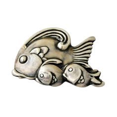 a silver brooch with two fish on it