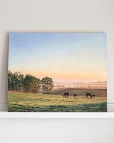 three horses grazing in a field at sunset