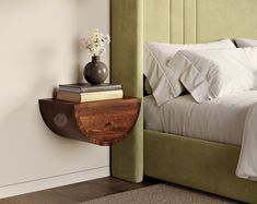 a bed with white pillows and green upholstered headboard next to a nightstand