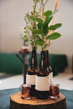 three beer bottles with flowers in them sitting on a table