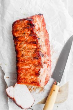 a piece of meat sitting on top of a cutting board next to a knife