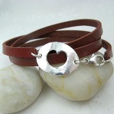 two leather bracelets with a silver circle on them sitting on top of some rocks