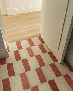 an orange and white checkered floor next to a tall door in a room with hardwood floors