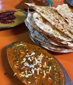 there are many different types of food on the table, including flatbreads and naan bread