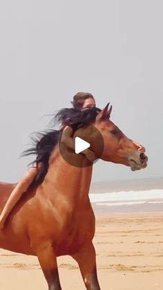 a woman riding on the back of a brown horse down a sandy beach next to the ocean