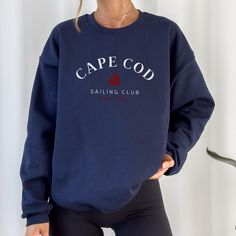 Elevate your seaside style with our Navy Crewneck Cape Cod Sailing Club Sweatshirt. Designed in a deep navy hue reminiscent of the Atlantic, it's the perfect companion for breezy days by the harbor or cozy evenings around a beach bonfire. Whether you're strolling along the picturesque Cape Cod coastline or enjoying a leisurely sail, this sweatshirt, adorned with the club emblem, embodies the maritime charm of the region. Crafted for both comfort and durability, it's equally suited for a day of adventure on the water or simply lounging at your favorite coastal cafe. Join the ranks of coastal enthusiasts and embrace the allure of Cape Cod with our signature sweatshirt. Navy Casual Crew Sweatshirt, Casual Navy Crew Top, Navy Crew Top With Relaxed Fit, Navy Casual Crew Neck Sweater, Marine Style Cotton Crew Neck Top, Navy Crew Neck Top With Letter Print, Navy Long Sleeve Marine Top, Navy Crew Neck Sweater With Letter Print, Navy Relaxed Fit Crew Top