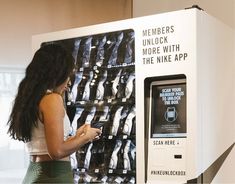 a woman standing in front of a machine that is displaying shoes on it's sides