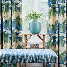 a blue bench sitting in front of a window covered in curtains and a vase on top of a table