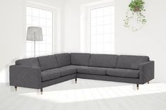 a living room with a gray sectional couch and potted plant on the wall next to it