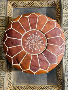 a brown and white ottoman sitting on top of a tile floor next to a wooden frame