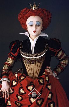 a woman with red hair and makeup wearing a costume that has hearts painted on it