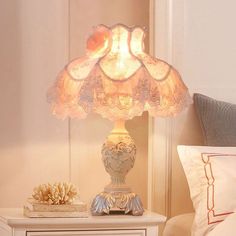 a lamp that is sitting on top of a table next to a bed with pillows